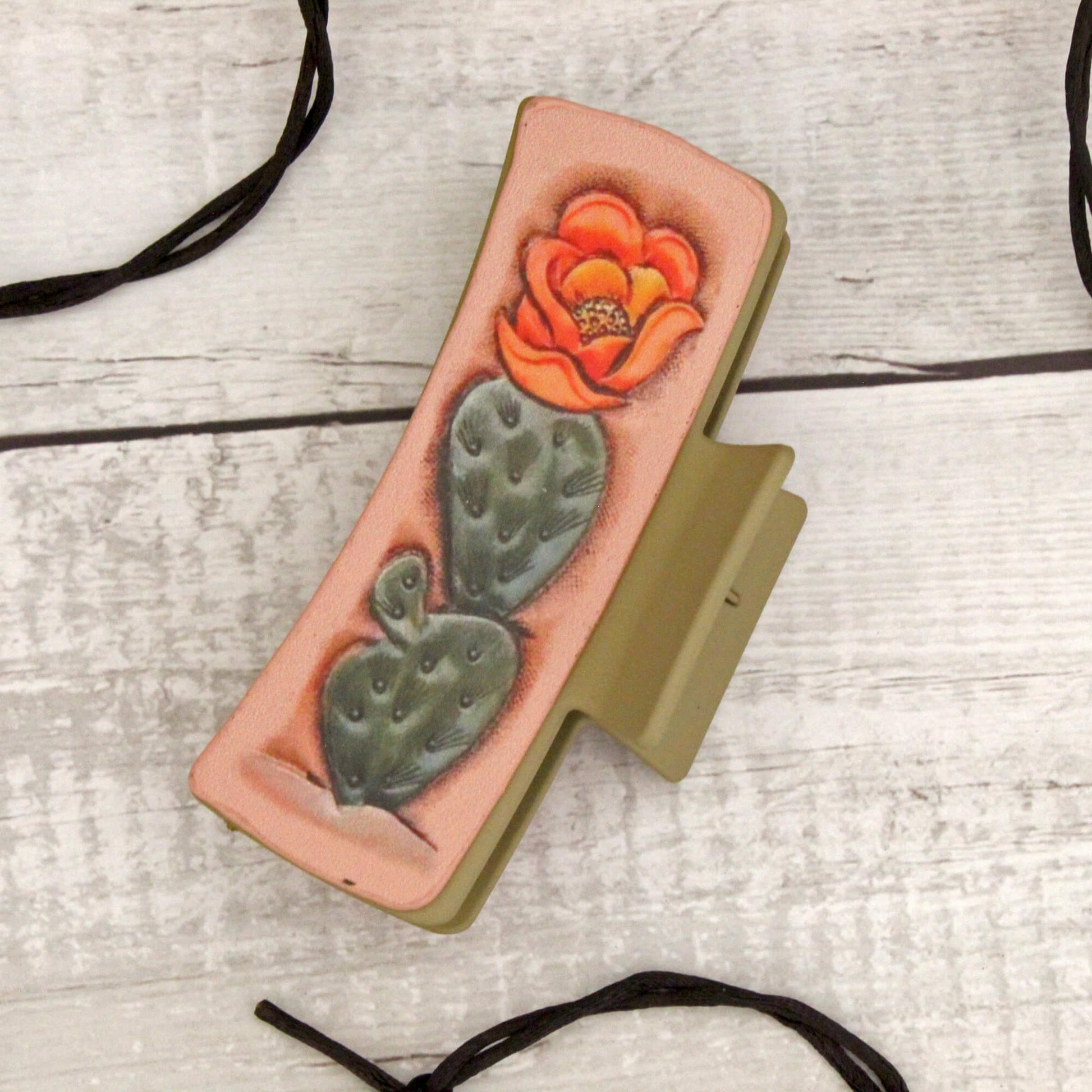 Western hair claw with a cactus and flower design on a wooden surface