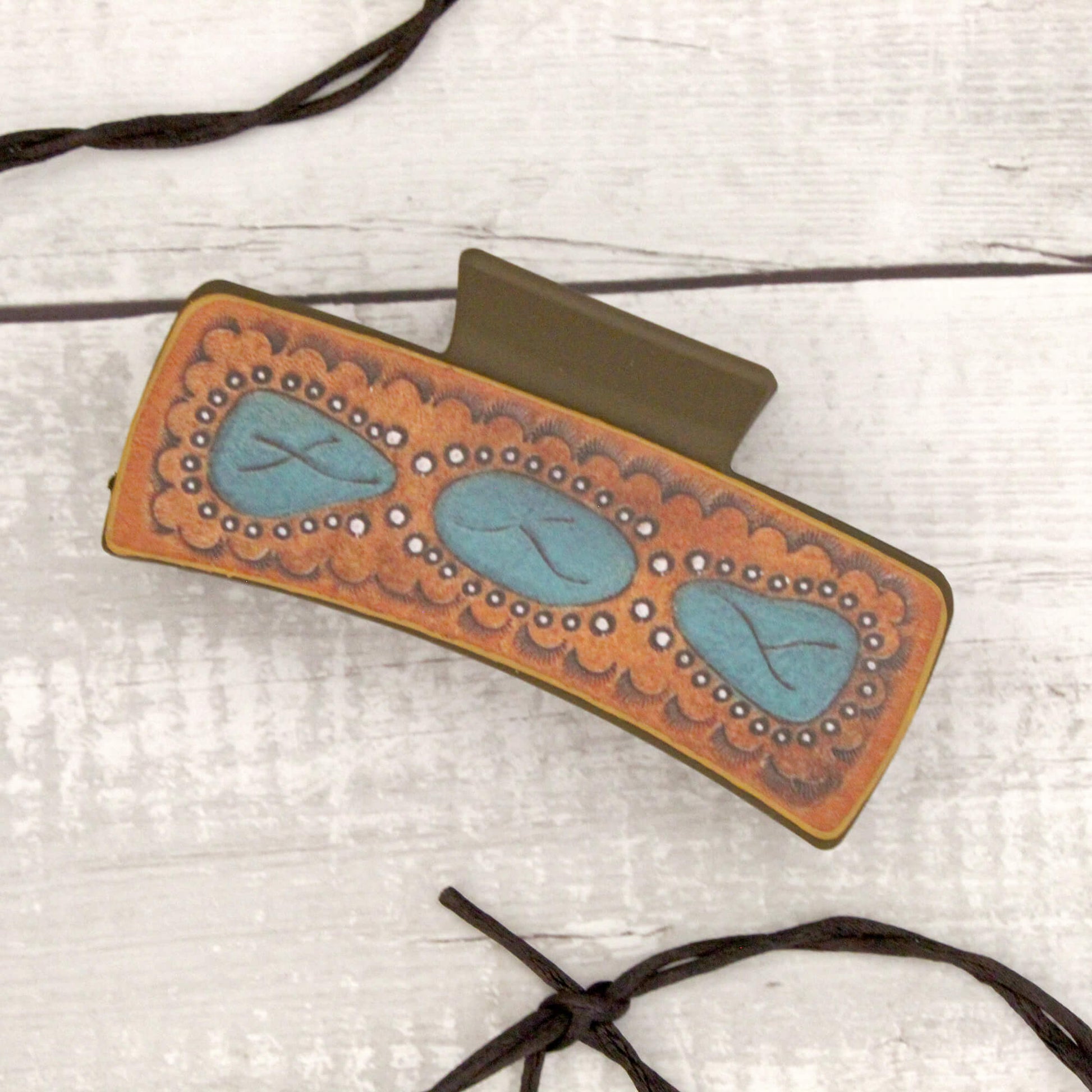 Decorative hair clip with turquoise stones on a light wooden surface