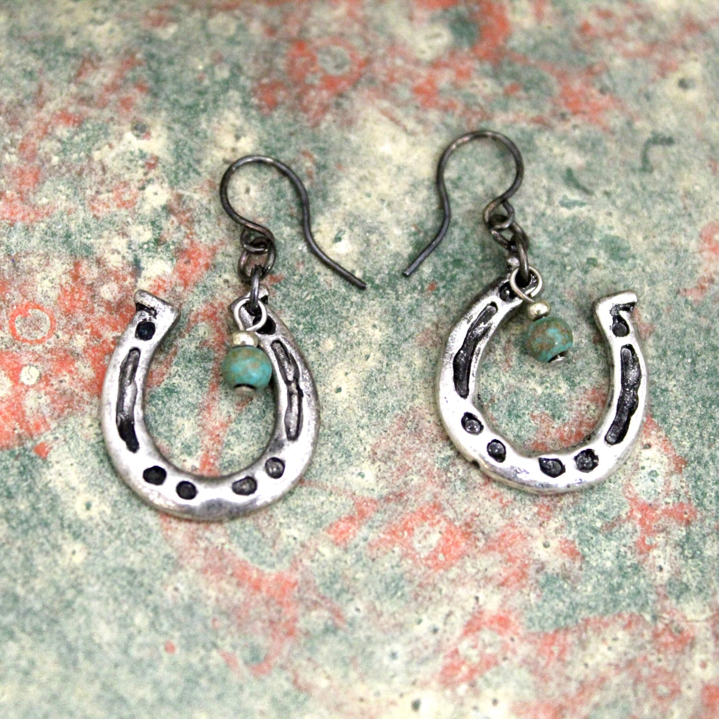 A simple yet fun set for you. The hypoallergenic ear wire holds right side up horseshoe pendants adorned with a mag Turquoise bead. Measures 1″ from bottom of the ear wire to the bottom of the earring.