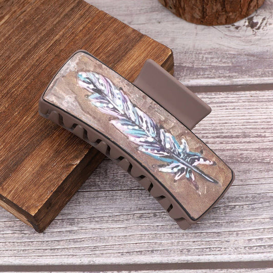 Decorative hair clip with feather design on a wooden surface