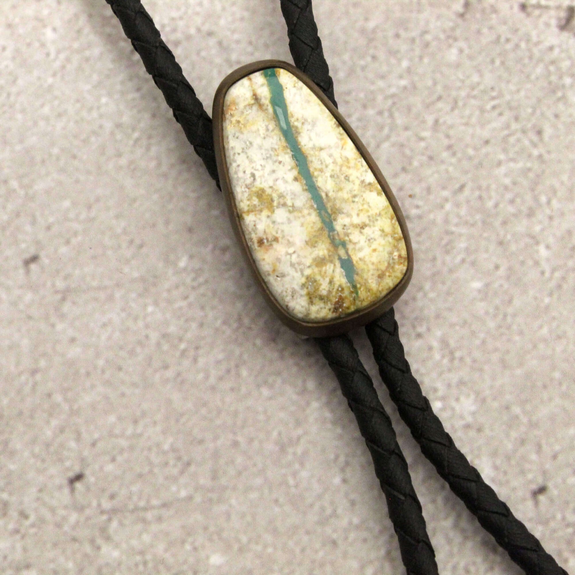 Bolo tie with a stone-like pendant on a textured surface