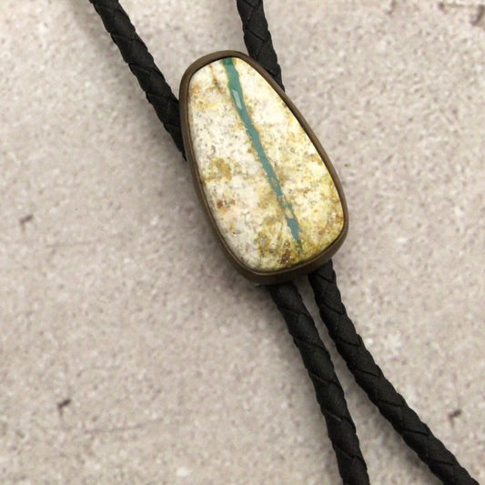 Bolo tie with a stone-like pendant on a textured surface