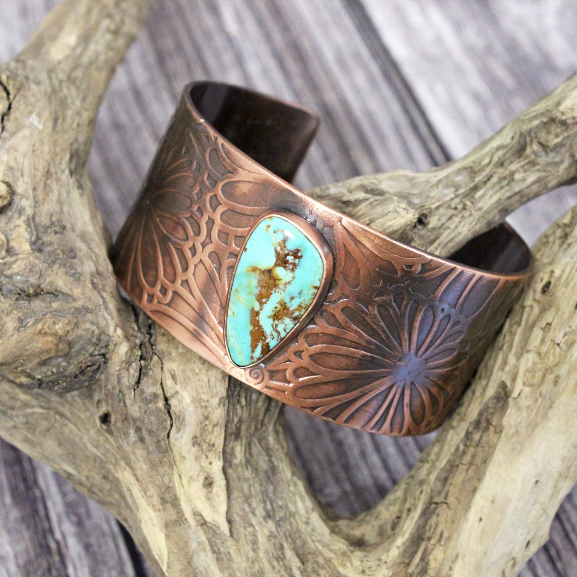 This heirloom-quality copper cuff is a true work of art, blending rustic charm with sophisticated elegance. The intricate flower design and vibrant turquoise stone create a mesmerizing focal point that will have everyone asking where you got it. Whether you're a cowgirl at heart or simply love unique, high-quality jewelry, this cuff is destined to become your new signature piece. Handcrafted 1.5" wide sturdy copper cuff. Bends slightly to fit most wrists.