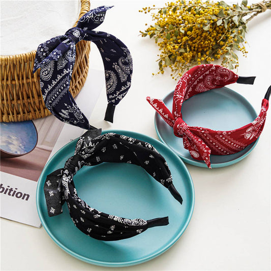 Three patterned headbands on blue plates with a basket and flowers in the background.