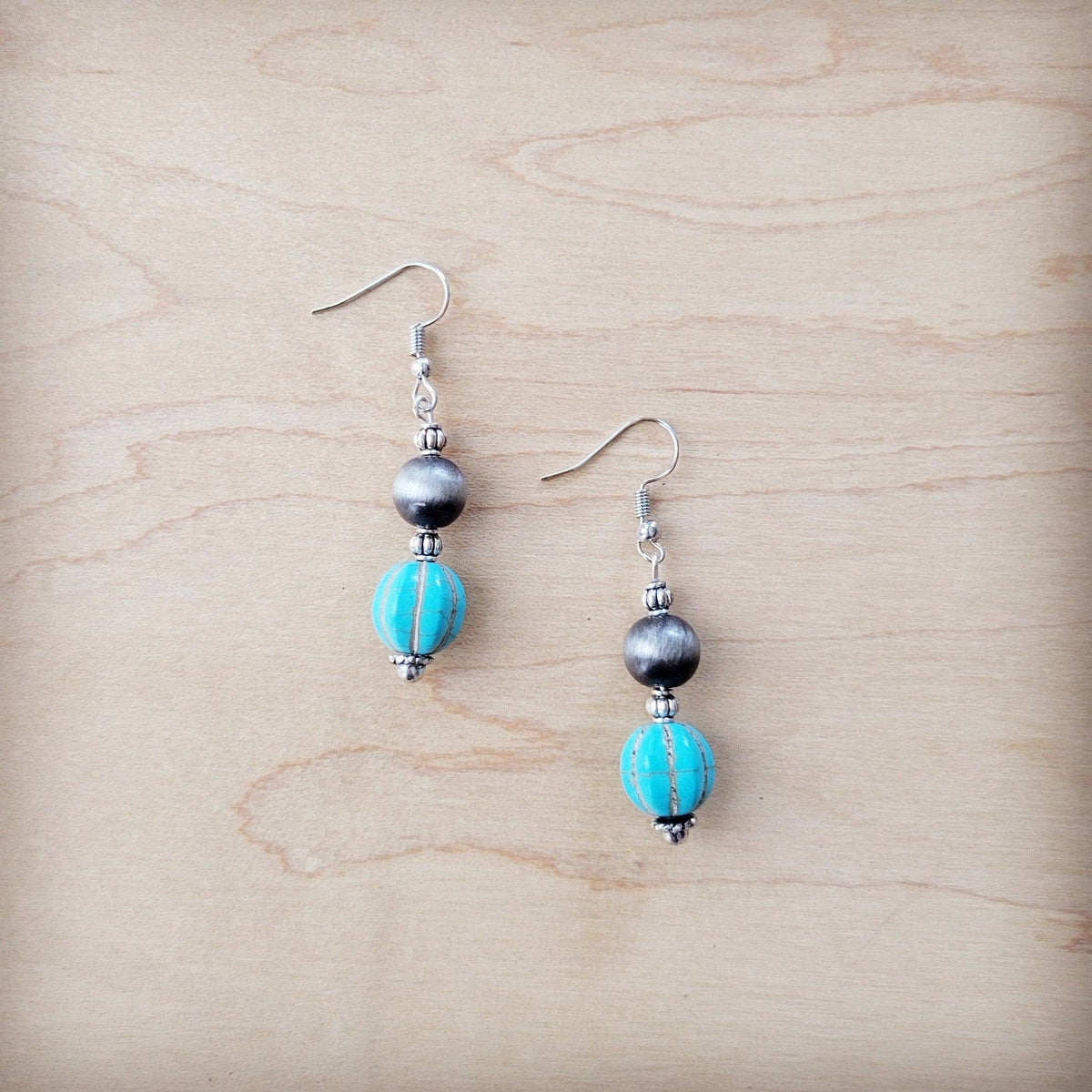 Pair of earrings with turquoise beads on a wooden surface