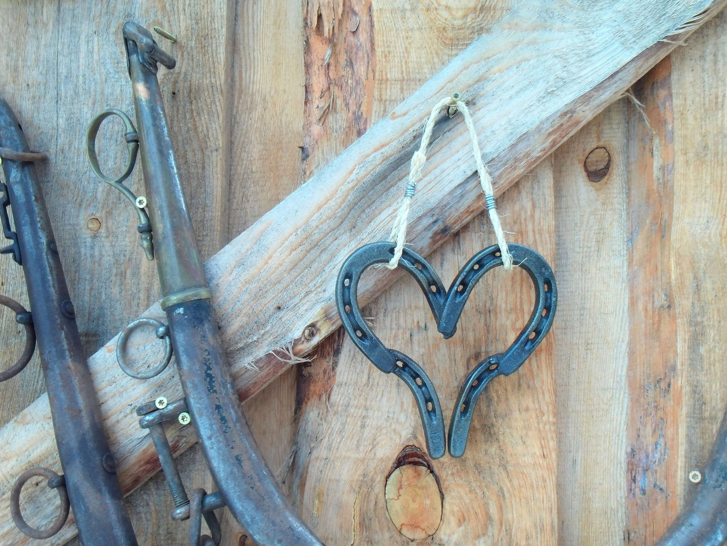 Welded Lucky Western Horseshoe Hanging Heart displayed on rustic wood background, symbolizing love and good luck.