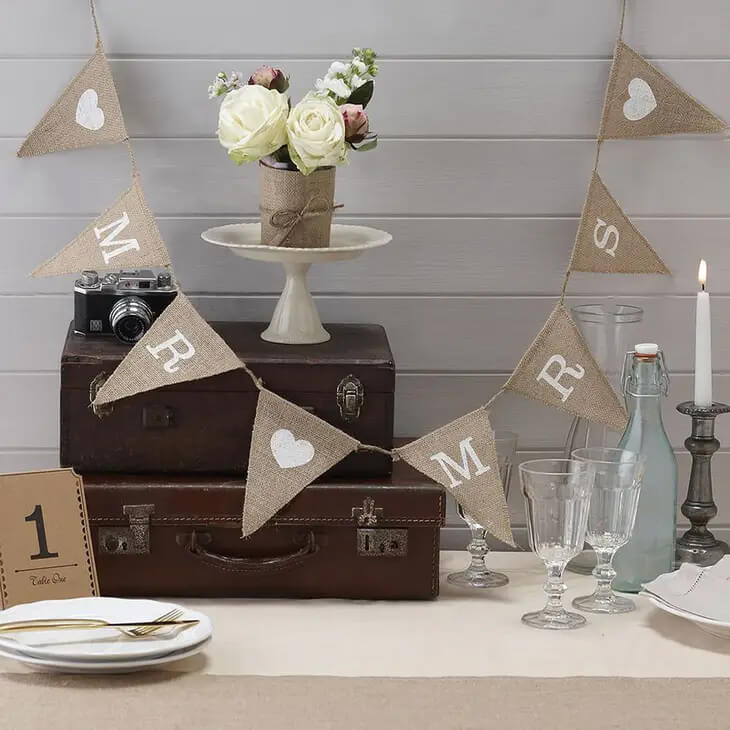 The hessian bunting is a great way to add a rustic feel to your wedding reception. The hessian fabric triangles attached to hessian string is printed with white text saying 'Mr' 'Mrs' separated by romantic white printed hearts. The wedding bunting is approximately 5 feet long.