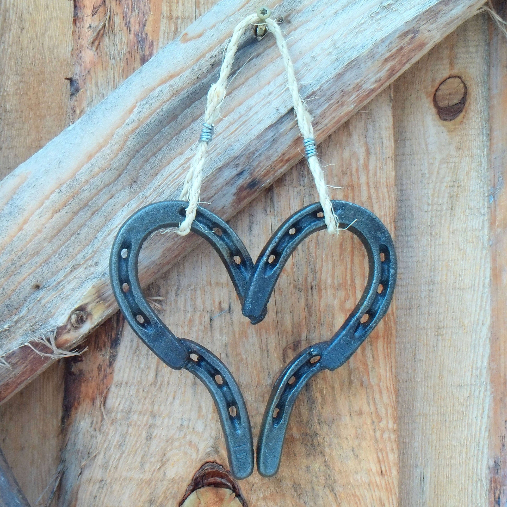 Welded Lucky Western Horseshoe Hanging Heart on rustic wooden background.