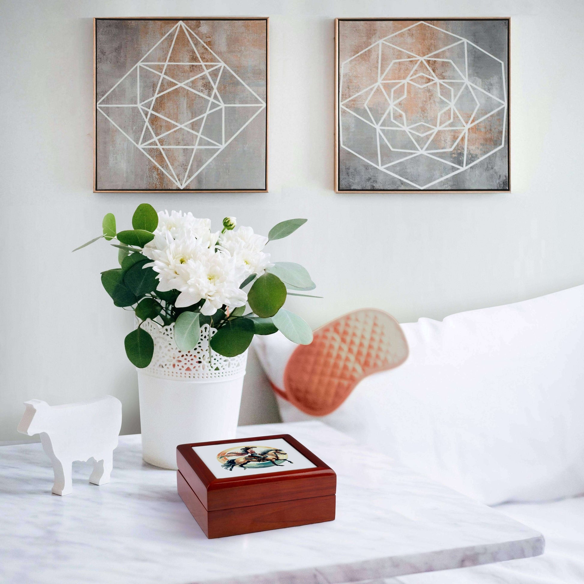 Decorative scene with a wooden box, white flowers in a vase, and geometric wall art in a room.