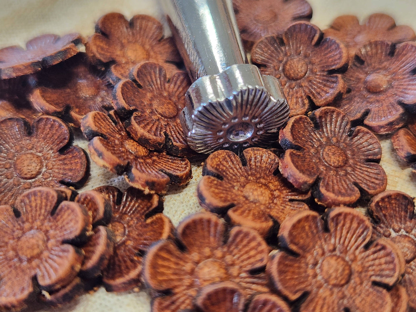 Metal flower-shaped stamp on a pile of wooden flower carvings