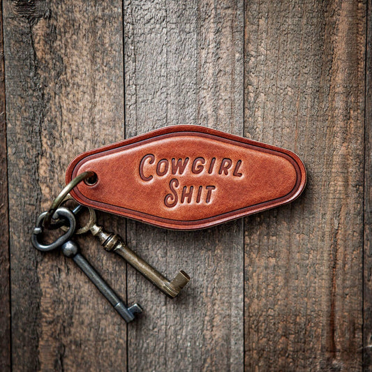 Cowgirl Shit Leather Keychain Motel Style featuring a bold stamp on rustic wood background.