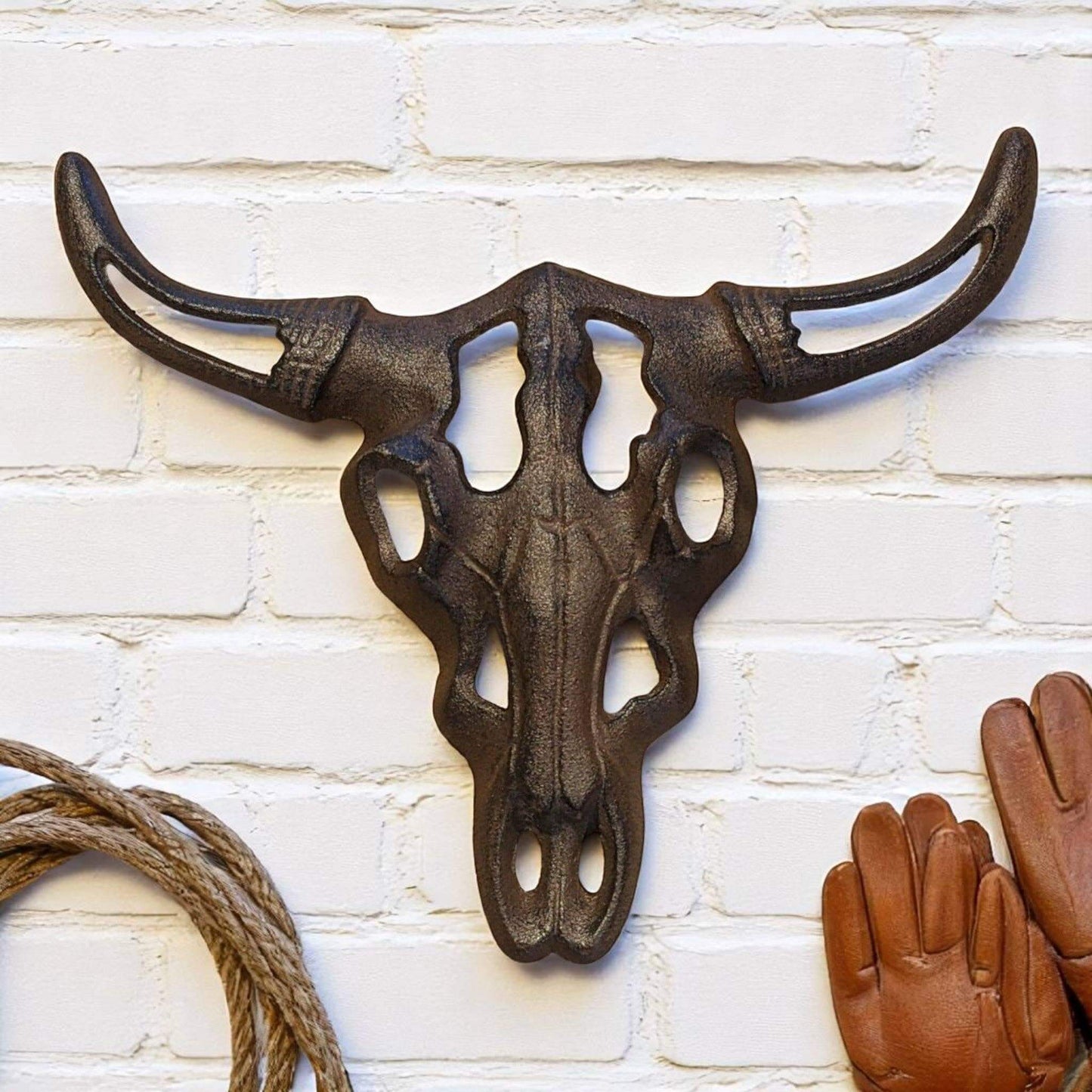 Cast Iron Bull Skull Wall Decor showcasing detailed rustic design with weathered finish mounted on a white brick wall.