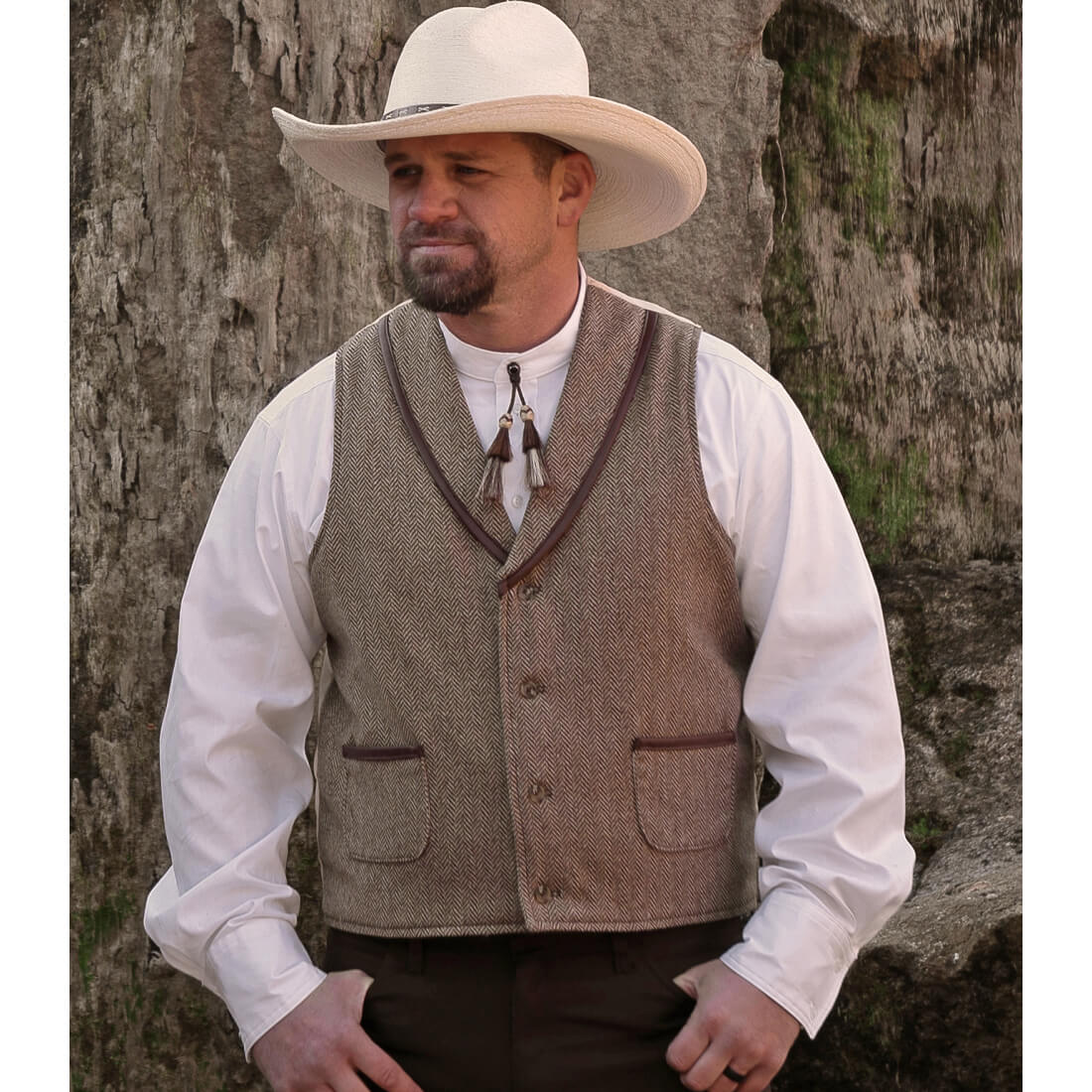 The fashionable look of this western wool vest is the perfect addition to your western outfit. This vest has simple style with faux leather trim on the shawl collar and pockets. The back of the vest is made of satin polyester that compliments the Herringbone Wool. Look like the best-dressed cowboy in the West! Fully Lined. Dry clean Recommended. Made in USA.