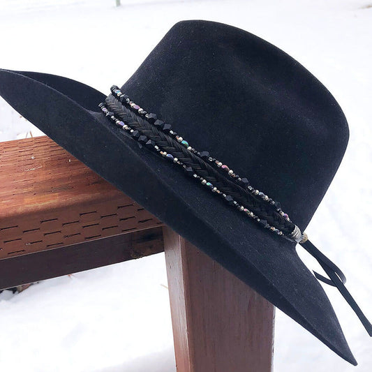 Stunning sophistication, this triple strand hatband, has a black seven strand braid of Authentic horse hair offset by dual strands of cool glass tubes, jet black cones and shimmering dusty heather freshwater pearls. Finished with sunburst conchos and leather tassels. Secured with a knot of horse hair. One size fits most hats. Hat not included. Made in USA