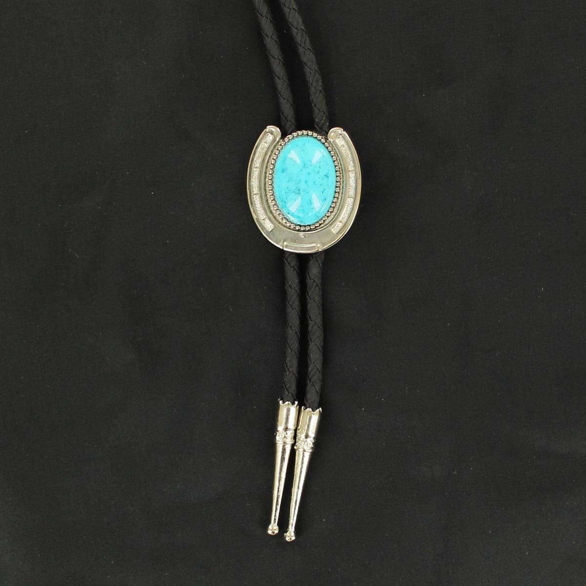 The official neckwear of cowboys also known as bola ties, we offer this horseshoe shape design with an oval turquoise stone. German silver with genuine black stone. Comes on a black braid and approximately 36”-37” long.